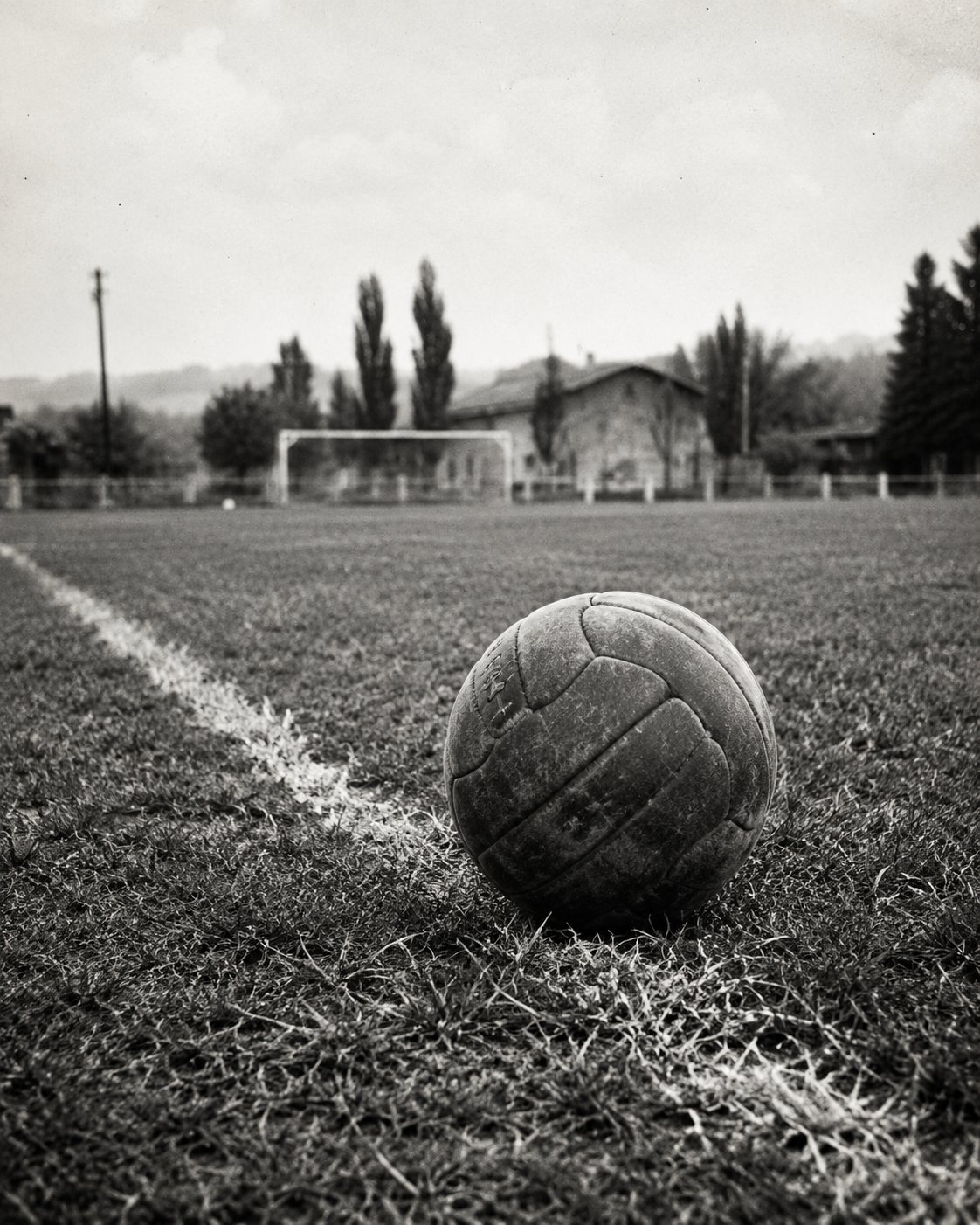 Un vecchio pallone di cuoio sulla linea di un campo di calcio di paese